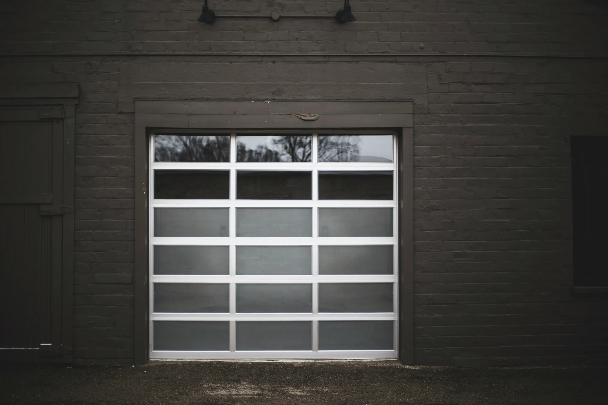 A modern garage door made of frosted glass panels in a white frame